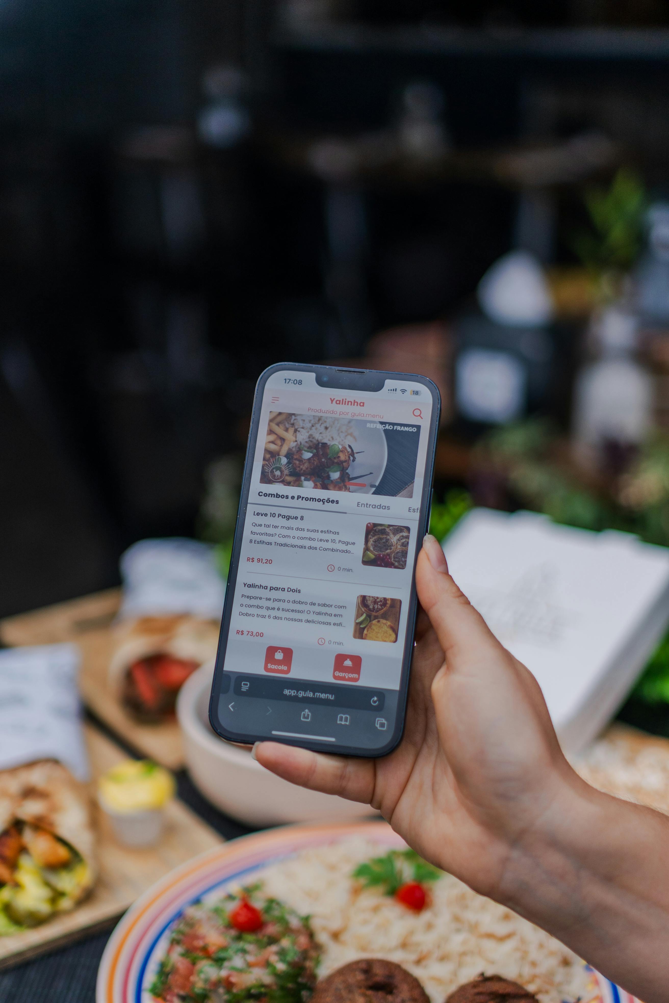 Hand hält Smartphone mit Restaurant-App über Essen